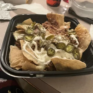 a plate of nachos with cheese and jalapenos