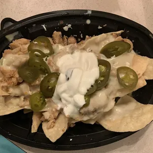 a plate of nachos with sour cream and jalapenos