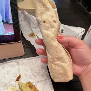 a person holding a burrito in their hand