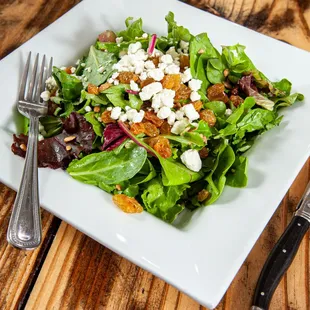 a plate of salad on a wooden table