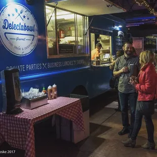 two people standing in front of a food truck