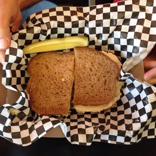 a person holding a sandwich with a pickle