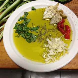 a bowl of olive oil, bread, and vegetables