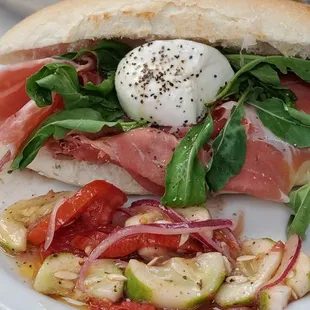 prosciuto burata panino with arugula and cucumber tomato salad on the side