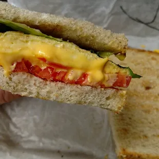 Side shot of lettuce and tomato on egg and cheese breakfast Sammie.
