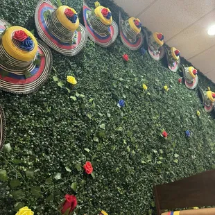 a wall of flowers and hats