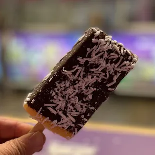 a hand holding a chocolate covered ice cream bar