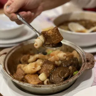a person dipping a piece of bread into a bowl of stew