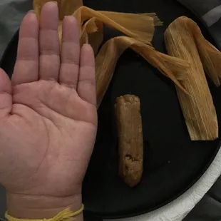 a person holding a plate of tamales