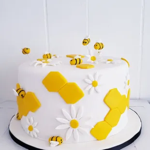 a cake decorated with bees and daisies