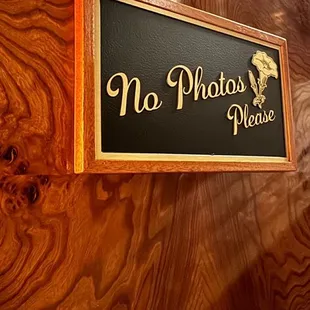 a no photos please sign on a wooden wall