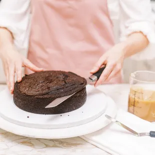 a woman cutting a chocolate cake