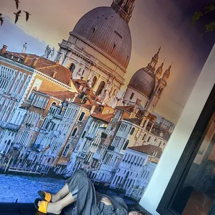 a man laying on a bench in front of a mural