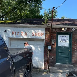 a man standing in front of a pizza shop