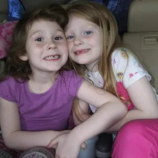 two young girls sitting in the back of a car