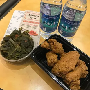 a tray of fried chicken and a bowl of greens