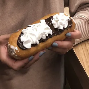 a woman holding a chocolate covered donut