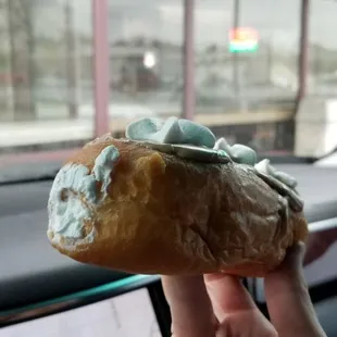 a hand holding a doughnut in a car