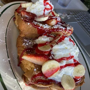 a plate of french toast with strawberries and bananas