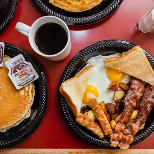 a breakfast of eggs, sausage, pancakes, and coffee