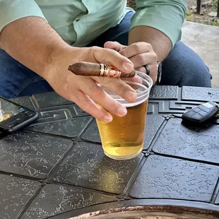 a man holding a cigar and a glass of beer