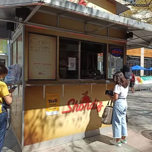 two people standing at a food stand