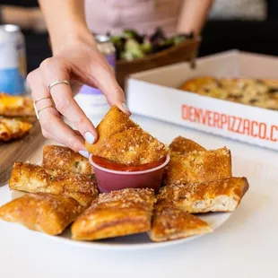 a person dipping a piece of pizza into a bowl