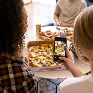 a woman taking a picture of a pizza