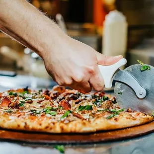 a person slicing a pizza