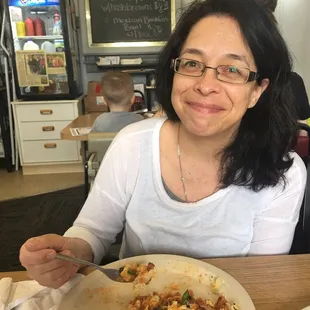 a woman sitting at a table with a plate of food