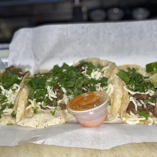 Three steak tacos with cheese and cilantro!
