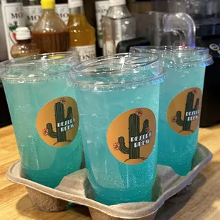 three cups of blue liquid in a carton