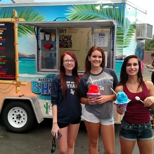 three girls standing in front of a food truck