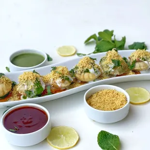 a platter of appetizers and dipping sauces
