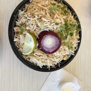 a bowl of rice with onions and a lime