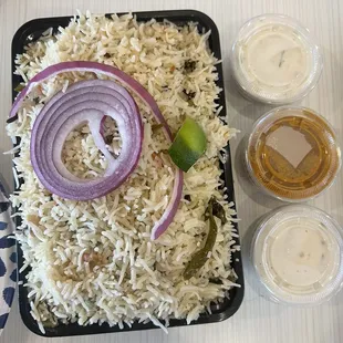 a plate of rice with onions and a lime