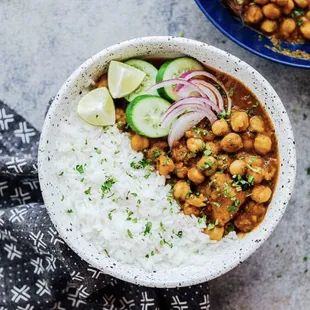 a bowl of chick curry with rice and cucumbers