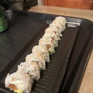 a long roll of sushi on a black plate