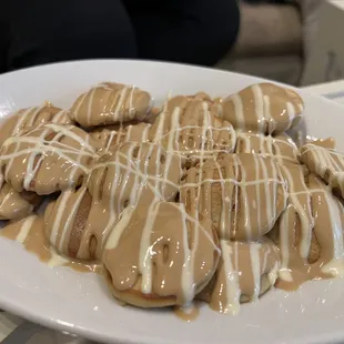 Freshly-made tiny pancakes drizzled with gooey caramel-like topping