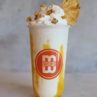 a banana milkshake topped with whipped cream and a pineapple