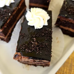 Moist chocolate sponge cake sandwiching rich Callebaut ganache and crowned with whipped cream and chocolate crumbs