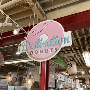 a pink donut sign hanging from the ceiling