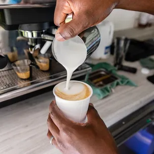 a person pouring milk into a cup