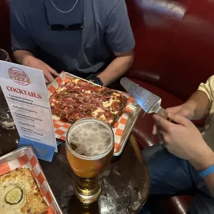 two men eating pizza and drinking beer