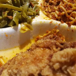 a plate of food that includes green beans, pasta, and meat