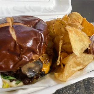 a burger and chips in a styrofoam container