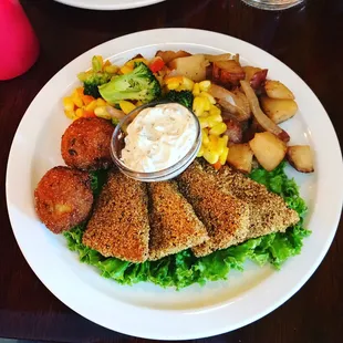 &quot;Catfish&quot; tofu with flavorful cornmeal breading, vegan tartar sauce, sautéed corn and broccoli, smothered potatoes, and hush puppies.