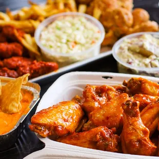 a tray of chicken wings with a side of coleslaw