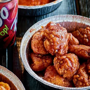 a can of soda and trays of chicken wings