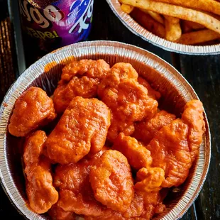 a bowl of wings and a can of soda